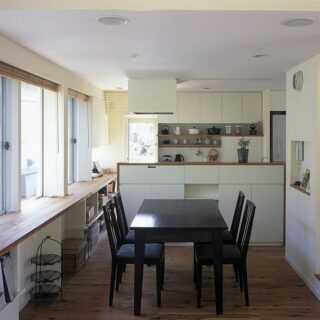 ダイニングとキッチン。造作キッチンで、手元が見えないように配慮している。冷蔵庫・洗剤・調味料など生活感があるものは見えないようにする一方で、見せる収納も意識。キッチン背後に飾り棚を用意した
撮影：石黒 守