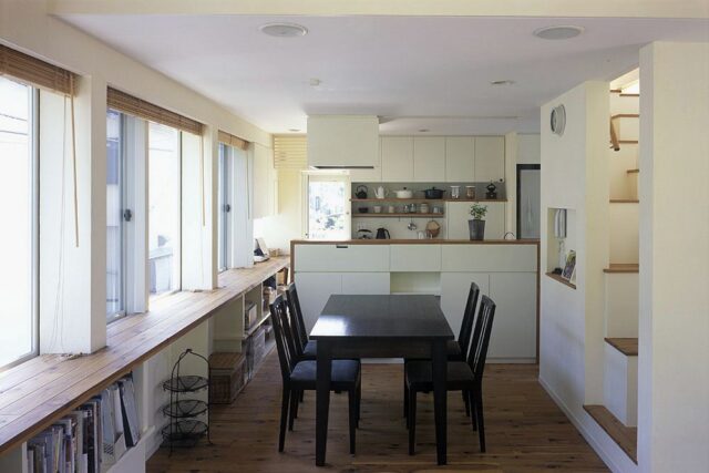 ダイニングとキッチン。造作キッチンで、手元が見えないように配慮している。冷蔵庫・洗剤・調味料など生活感があるものは見えないようにする一方で、見せる収納も意識。キッチン背後に飾り棚を用意した
撮影：石黒 守