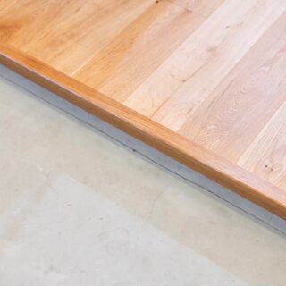 玄関のたたきとフローリング。段差を抑え、上がり框は細くすることでシンプルさを追求した。オーク材無垢の2ｍｍ厚節付きフローリングを採用。価格を抑えられるだけでなく傷や汚れが目立たないメリットもある。下地は遮音性能LL-45相当の二重床で下階に配慮した。