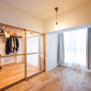 寝室から見たドライルーム。ガラス框扉で空間全体が明るく広く見える。賃貸に出した時、入居者募集の写真映えまで考えての採用だ。子どもが小さいので、寝室は布団を敷き詰めて使用。壁一面にハンガーパイプを配置して大容量のクローゼットも兼ねている。