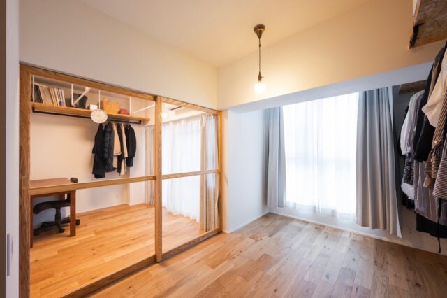 寝室から見たドライルーム。ガラス框扉で空間全体が明るく広く見える。賃貸に出した時、入居者募集の写真映えまで考えての採用だ。子どもが小さいので、寝室は布団を敷き詰めて使用。壁一目にハンガーパイプを配置して大容量のクローゼットも兼ねている