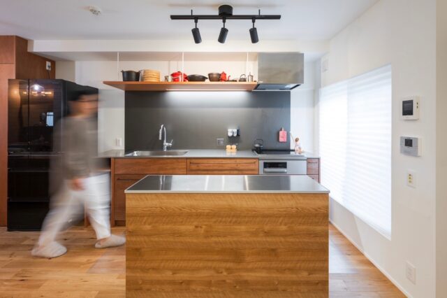 キッチン。IHを採用し、80年代のヴィンテージマンションはオール電化に変貌した。照明だけでなく右側の光庭からも光が入り、明るいレイアウトだ。手前のカウンターは造作に見えるが通販で買ったもので、自由に移動できる