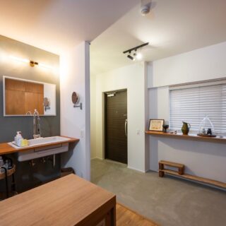 玄関。独立していた玄関を、ファミリールームと一体のコンクリート土間とすることで空間に面する窓を増やし、広がり感だけでなく、通風や採光を豊かにした。帰宅後すぐに手洗いができるよう、洗面位置を変更。大きな鏡で空間を大きく見せる効果も。