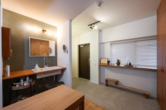 玄関。独立していた玄関を、ファミリールームと一体のコンクリート土間ととすることで空間に面する窓を増やし、広がり感だけでなく、通風や採光を豊かにした。帰宅後すぐに手洗いができるよう、洗面位置を変更。大きな鏡で空間を大きく見せる効果も。