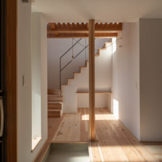 玄関ホール。木材は無垢の杉、白壁はドイツ製のウッドチップ入り紙クロス。自然志向の素材を使ったナチュラルモダンな空間に、大谷石の壁（写真右）が本物志向の上質感をプラス。過度にならない上品な高級感がいい