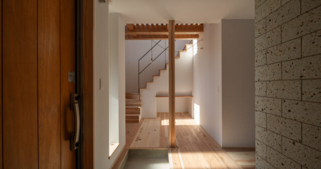 玄関ホール。木材は無垢の杉、白壁はドイツ製のウッドチップ入り紙クロス。自然志向の素材を使ったナチュラルモダンな空間に、大谷石の壁（写真右）が本物志向の上質感をプラス。過度にならない上品な高級感がいい