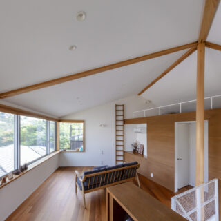 2階、書斎からリビング、ロフトを見る。切妻屋根側のリビングは天井が高く開放的。一面を大開口した南側には鎌倉山の景色が広がり贅沢だ。木板が貼られた右側の箱の中は寝室とトイレ。リビング側に収納を計画し、寝室内の壁が直角になるよう計画。場にふさわしい落ち着きを実現