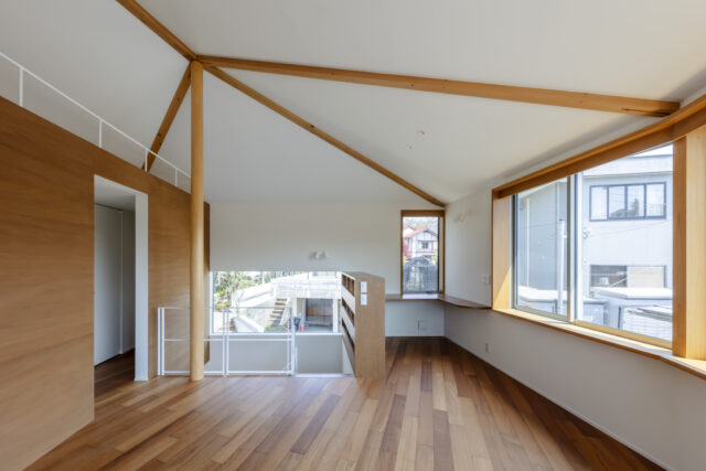 2階。南側の大開口にも緩やかに角度がついているうえ、正面の書斎の細い窓、左に続く階段の窓と方向や高さが異なる窓が並び、移動時に自然に景色や光の雰囲気が切り替わる。表情の異なる明るさと、存分に入る日射による暖かさは五角形の建物の特徴を生かした豊かさのひとつ