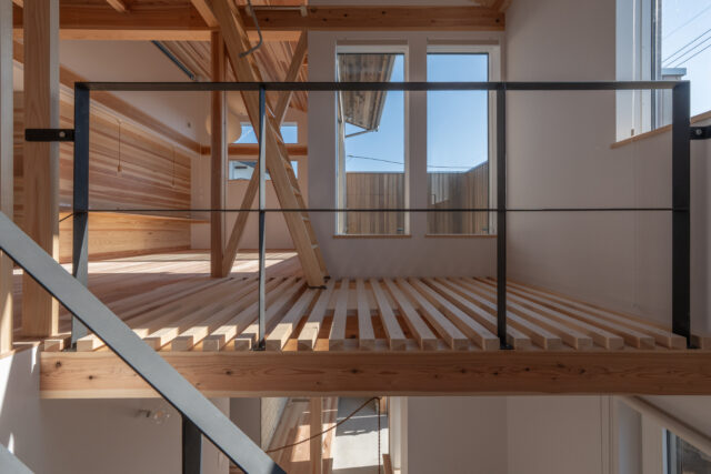 階段からの眺め。ソラドマ（2階バルコニー）に面した大きな窓は、冬に真南の暖かな日射を得るという大役を担っている。手前の床は目透かし板にして、空気の循環や1階の明るさを担保。丁寧な職人技が光る目透かし板はインテリアとしても美しい