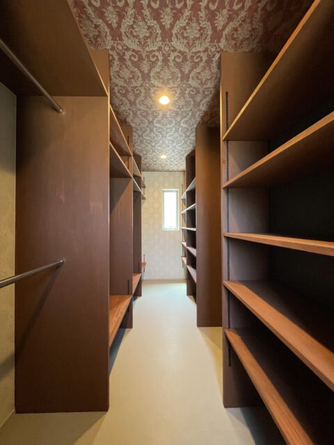 棚やハンガーラックが並ぶ大容量のWIC。天井には高級感ある壁紙を採用した。
