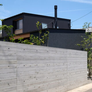 外観。周囲と馴染むことを期待し、外構のコンクリートには無垢の杉板を型枠として使用した。実際に板を張ったことにより表情がさまざまで、コンクリートでありながら有機的な雰囲気がある。住宅街にあるため、庭の中の様子は外からは見えないようにした