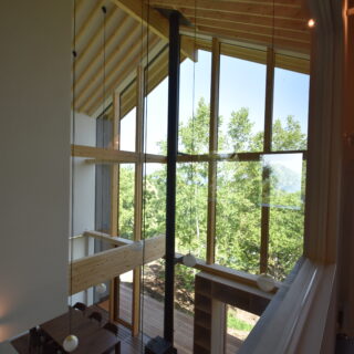 2階、洋室2からの眺め。森の向こうに洞爺湖を望む。梁が窓へとまっすぐ伸び意識が外へいざなわれる