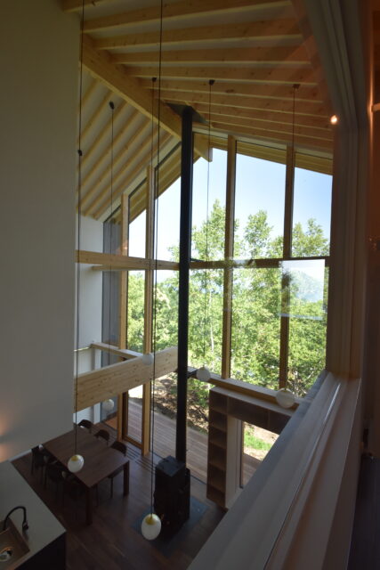 2階、洋室2からの眺め。森の向こうに洞爺湖を望む。梁が窓へとまっすぐ伸び意識が外へいざなわれる

