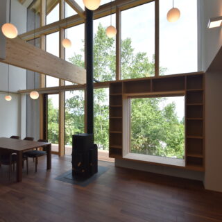 1階LDK。丸いライトは湖に浮かぶ中島をイメージ。中央のストーブは取り入れやすいハイブリッド式を採用

