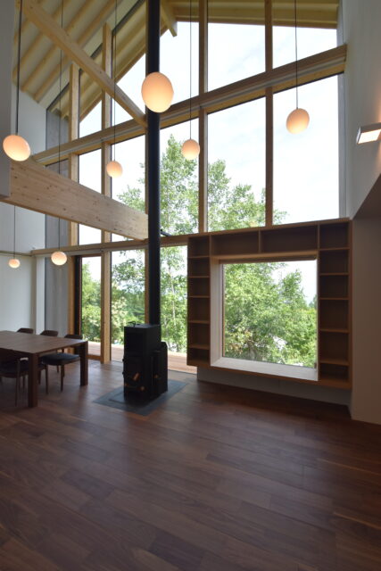 1階LDK。丸いライトは湖に浮かぶ中島をイメージ。中央のストーブは取り入れやすいハイブリッド式を採用
