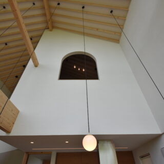 1階LDKから2階寝室を見上げる。寝室の小窓にも中島の稜線と調和するアールをつけた
