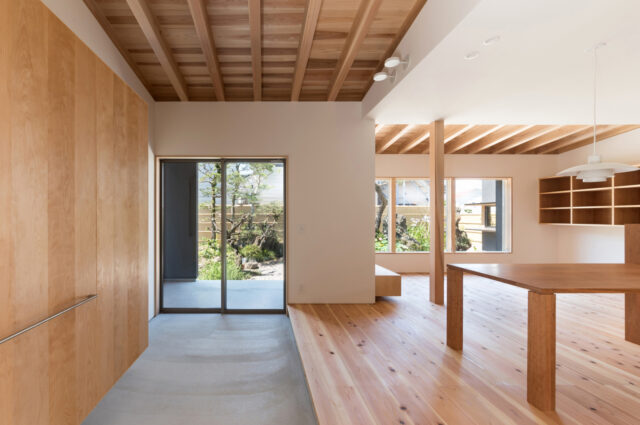 玄関から土間、テラス、LDKのワンルーム空間を見る。正面の掃き出し窓は「庭と繋がる窓」。奥のテラスでは天候関係なく庭を楽しめる。土間の収納には靴以外にもコートなどを収納できる。現在は土間に薪ストーブを設置。冬場は空間全体を温め、一層ゆったりとした時間が流れる