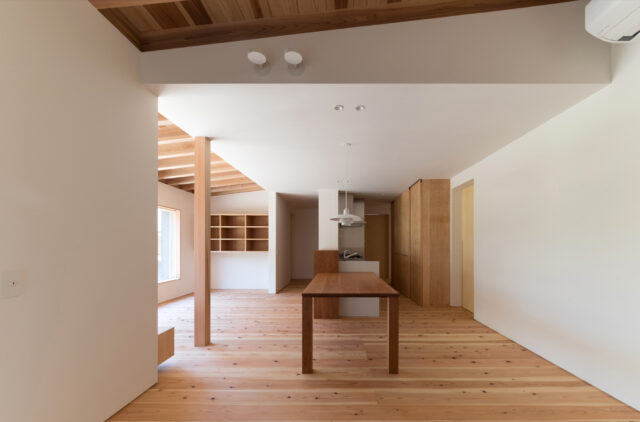 玄関土間からLDKを見る。右壁面の引き戸は勝手口や階段、洗面・脱衣室に繋がる。隠れているが続く収納の奥にも引き戸があり洗面・脱衣室と繋がる。天井を設けたキッチン、ダイニングに比べリビングや土間は天井が高く、感覚的にエリアが区切られ過ごしやすい