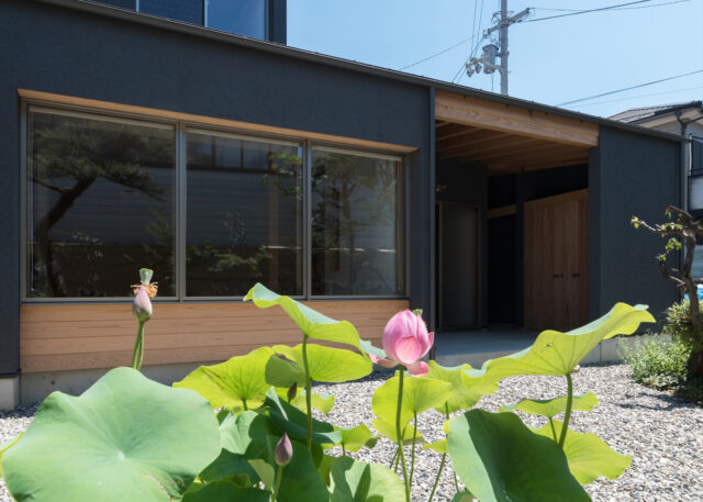 庭から「庭を眺める窓」とテラスを見る。立面的なバランスを考え、窓を出すのではなく奥まらせ、その幅を活用し庇の役目を持たせた。ジョリパットの質感豊かな黒い塗壁と木材の表情を見せた外観はメリハリが効いており美しい