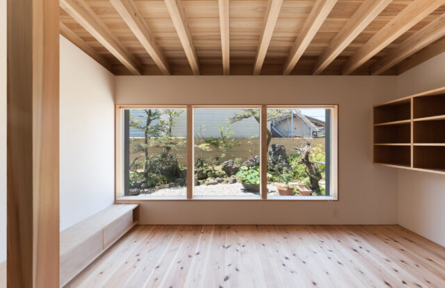 キッチン、ダイニングからリビング、「庭を眺める窓」を見る。庭をより美しく見せるため、FIX窓を採用。サッシやロックなどを一切見せず、すっきりした印象に仕上げた。枠に厚みを持たせることで視界の広がりを抑え、絵画のように庭の景色を切り取った