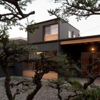 庭から家を見る。画像右、半屋外のテラスは土間と一続きになっており外に出やすい。キッチンからも近く、食事を楽しまれたりしているとのこと。建て替えにあたり、庭をどう残すかにも心を砕いたという樋口さん。植栽を増やしたり、砕石を敷いたりして整えた