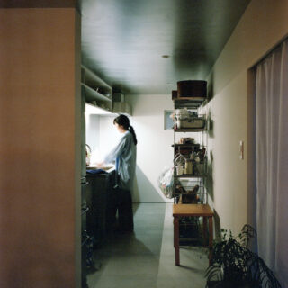 ホールの先のキッチンは領域を分かりやすく独立したイメージに。システムキッチンを採用しつつ、棚はあえてつくりつけとせず、可変性をもたせた。