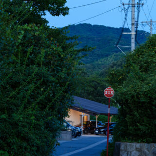 集落の入口となる道路から見た光景。片流れの低い屋根の効果で、その先に山などの景色を見ることができる