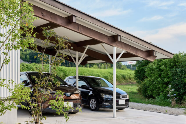 片流れ屋根のもっとも低い部分。屋根付き駐車場や作業などのフリースペースとして使われている。車を２台停められる、広大なエリアだ。長い張り出しなので、鉄製の支柱で強度を確保した