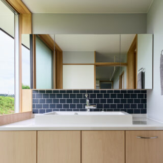 洗面。お客様も使うため、リゾート感あふれる、開放的な空間とした。脱衣スペースと洗面をゾーニングで分けることで、大きな窓を使用することが可能となった