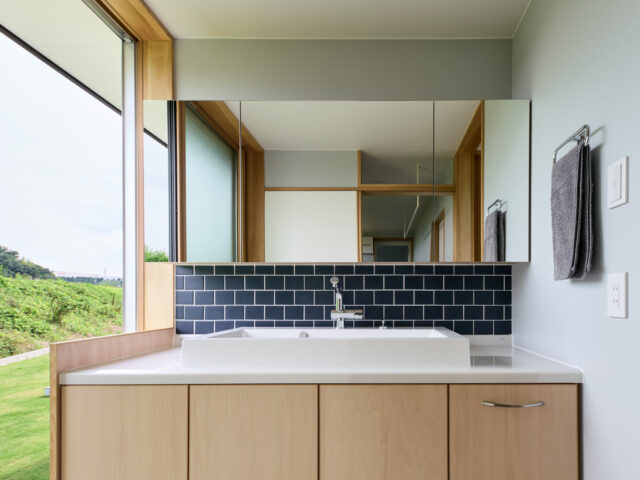 洗面。お客様も使うため、リゾート感あふれる、開放的な空間とした。脱衣スペースと洗面をゾーニングで分けることで、大きな窓を使用することが可能となった

