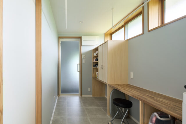 浴室（正面奥）へつながる脱衣所は、ランドリースペースと家事コーナー、衣類の収納スペースを兼ねている。ハイサイドライトの効果で明るい空間だ。左手前のドアは寝室につながっており、効率的な動線が考えられている