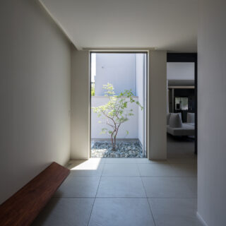 玄関正面には大きな窓で光と抜け感を。木製の飾り棚はベンチとしても利用でき、腰掛けながら靴が履ける