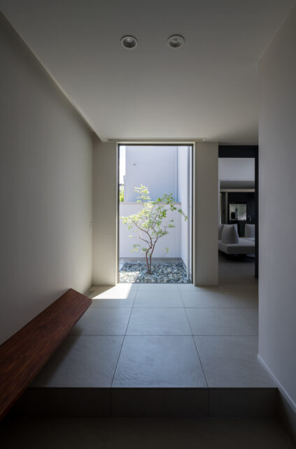 玄関正面には大きな窓で光と抜け感を。木製の飾り棚はベンチとしても利用でき、腰掛けながら靴が履ける。