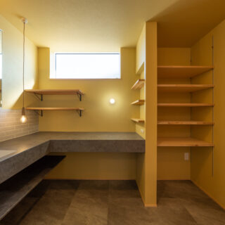 2階洗面室には大きな洗面カウンターを造作。内装は磁器質タイルや石目調のフロアタイルをセンス良く取り入れ、人に見せたくなるような空間に仕上げている。写真右の棚はタオルや部屋着の収納に最適。この洗面室はランドリールームとつながっていて、洗濯後はすぐにしまえる