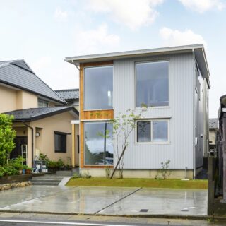 外観。1階右側の窓は寝室のもの。建物前の芝生部分、基礎が駐車場より一段高くなっているうえに腰窓としたことで、寝室の中は覗かれにくい。特殊な条件がない限り、外壁の耐久性や雨仕舞いを考慮し、軒の出を確実に設けているという。