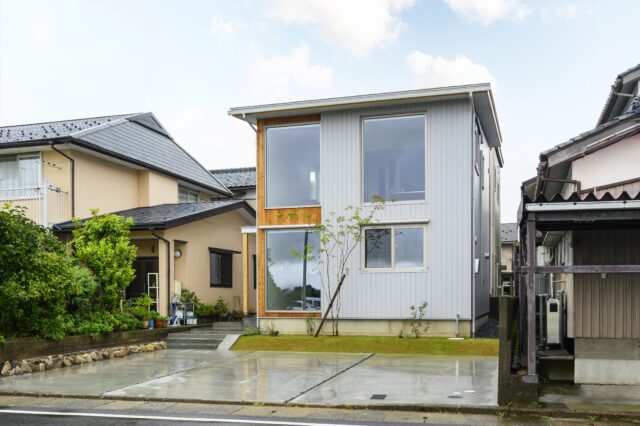 外観。1階右側の窓は寝室のもの。建物前の芝生部分、基礎が駐車場より一段高くなっているうえに腰窓としたことで、寝室の中は覗かれにくい。特殊な条件がない限り、外壁の耐久性や雨仕舞いを考慮し、軒の出を確実に設けているという。