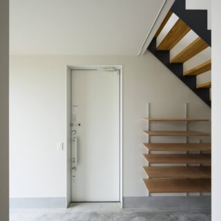 1階、玄関は壁と同じ白とし存在感を消した。画像左にある大窓や階段上の開口から豊かに光が入る。
