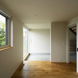 1階寝室から土間を見る。日陰になる場所を調査し、根拠を持って開口したことにより確実に光が入る。寝室からは植栽の緑も目に入り心地よい。廊下に向けて仕切り戸を設け、ファミリークローゼットやトイレ、個室への動線を計画した。