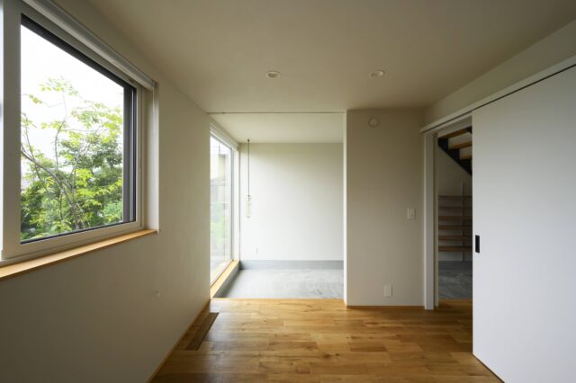 1階寝室から土間を見る。日陰になる場所を調査し、根拠を持って開口したことにより確実に光が入る。寝室からは植栽の緑も目に入り心地よい。廊下に向けて仕切り戸を設け、ファミリークローゼットやトイレ、個室への動線を計画した。