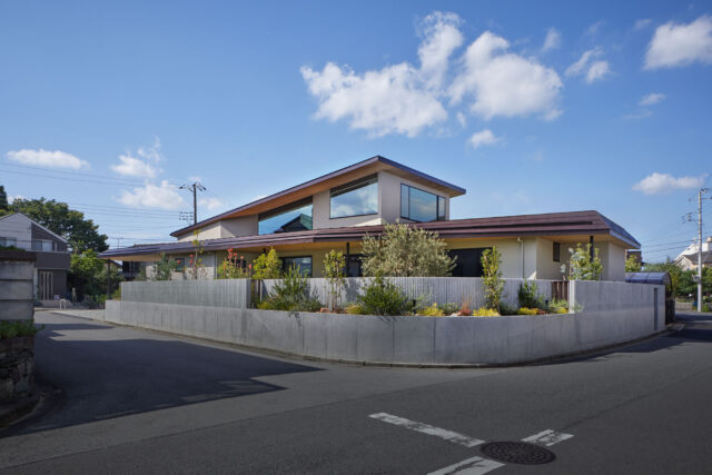 南から見た外観。プライバシーを守るための外構は、一部の植栽は道路に向けて開き威圧感を軽減。コンクリートはリブ付きとし、柔らかさをプラスした。まっすぐに伸びる１階の屋根と、捲り上がるような２階の屋根。どちらも伸びやかで、家に大らかさが感じられる