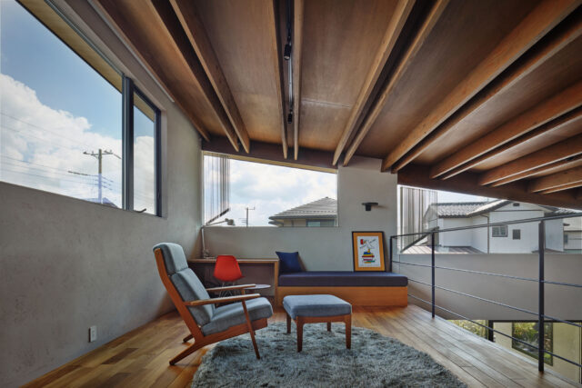 2階ロフト。木天井は強固に加工された建材を組み合わせ、梁成の細い、モダンな梁を実現した。２枚組み合わせた中にダクトレールを取り付け、天井の美しさは損なわずに明るさを確保。家の構成上斜めになった窓には縦型のブラインドを使い、日射や視線をコントロールする