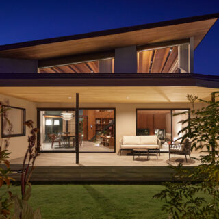 庭から家を見る。1階のデッキは明るく、また2階も屋根が持ち上がり、中からの光が屋根に反射して木の表情を美しく見せている。「木屋根の家」と名付けられた理由がよくわかる。2階ロフト部分は外部から眺められるが、壁の高さによって人の姿は見せず、光のみが漏れるよう計画