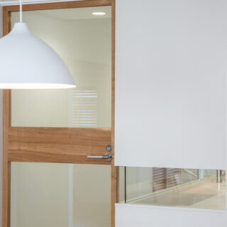 左はLDKに出入りするガラス扉。右はパウダールームを囲う壁。カラス扉は無垢のナラ材でつくった特注品。太めの中残とパウダールームの壁のガラス部分はサイズをそろえ、市松模様のようにデザインしている。こうした細やかな操作が、空間全体の端正な美しさをつくる