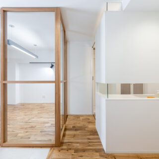 写真左が仕事の来客を想定したアトリエ。右がパウダールーム。無垢材を使った特注のガラス戸の中残は、パウダールームの壁の水平スリットと一直線になるように設計され、スッと気持ちよく通るラインが生まれている。こうしたさりげないデザインへのこだわりが空間の上質感を高める