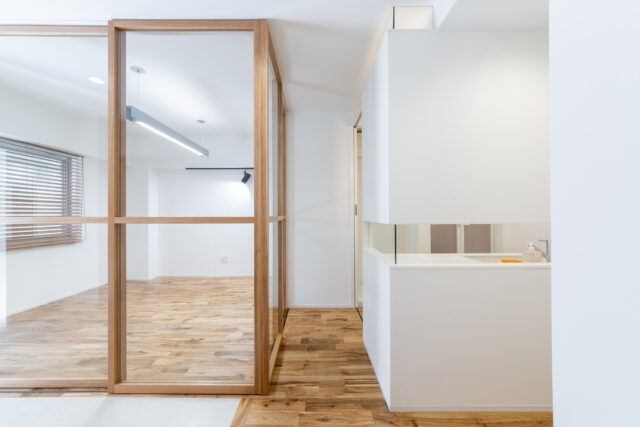 写真左が仕事の来客を想定したアトリエ。右がパウダールーム。無垢材を使った特注のガラス戸の中残は、パウダールームの壁の水平スリットと一直線になるように設計され、スッと気持ちよく通るラインが生まれている。こうしたさりげないデザインへのこだわりが空間の上質感を高める