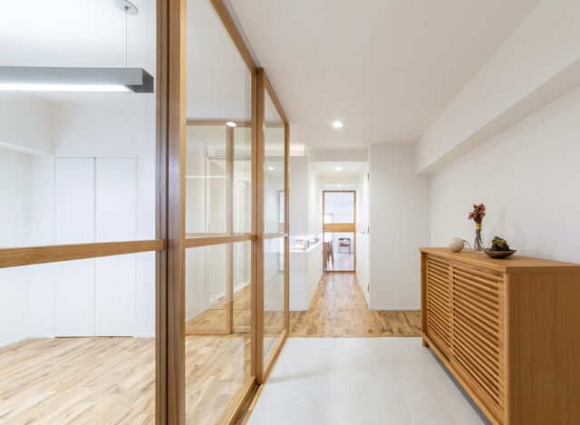 玄関からの眺め。仕事の来客対応を想定したアトリエ（写真左）のガラス戸を閉じると、ガラス戸の中桟、その奥にあるパウダールームの壁の水平スリット、奥のガラス扉の中桟が一直線になるように設計してある。奥行きを感じられ、本能的に美しいと思える空間