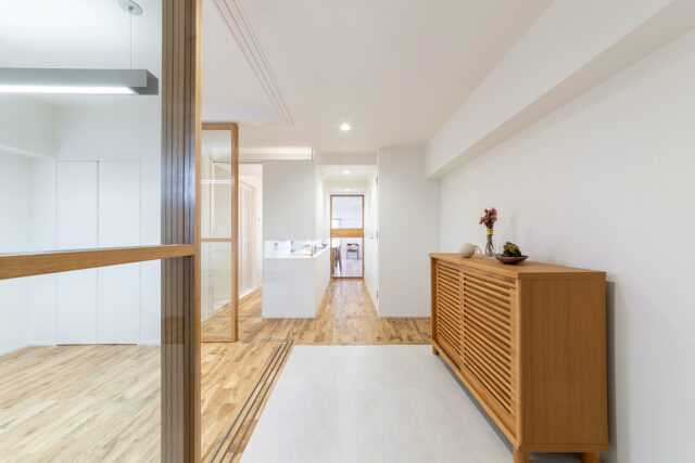 玄関から邸内を見る。アトリエ（写真左）のガラス戸を開けると玄関土間とひと続きになり、来客を迎えるのにふさわしいオープンな空間に。正面奥のLDKへ入るドアもガラス扉なので視線が通って閉塞感は皆無。LDKに入る光も玄関まで届き、とても明るい