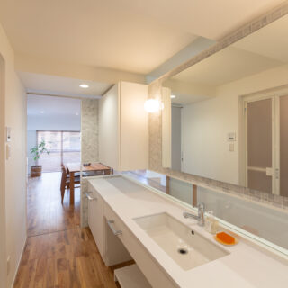 来客の使用も想定したパウダールームは、壁にダイス状の大理石をあしらったホテルライクなデザイン。オリジナルで設計したカウンターは広々。照明の落ち着いた光も心地よく、ゆったりとしたラグジュアリーな気分で手洗いや身支度ができる