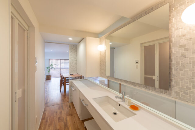 来客の使用も想定したパウダールームは、壁にダイス状の大理石をあしらったホテルライクなデザイン。オリジナルで設計したカウンターは広々。照明の落ち着いた光も心地よく、ゆったりとしたラグジュアリーな気分で手洗いや身支度ができる