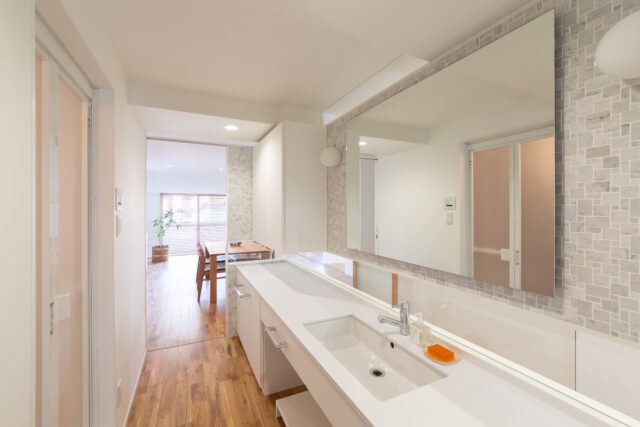 LDKと玄関の間に位置するパウダールームは両サイドを引き戸にし、正面の壁は水平スリットを入れ、宙に浮いているような軽やかなデザインで新調。引き戸を全開するとLDKの窓が見え、外の爽やかな自然を感じられる。光も風もスムーズに通り、邸内全体がぐっと明るくなった